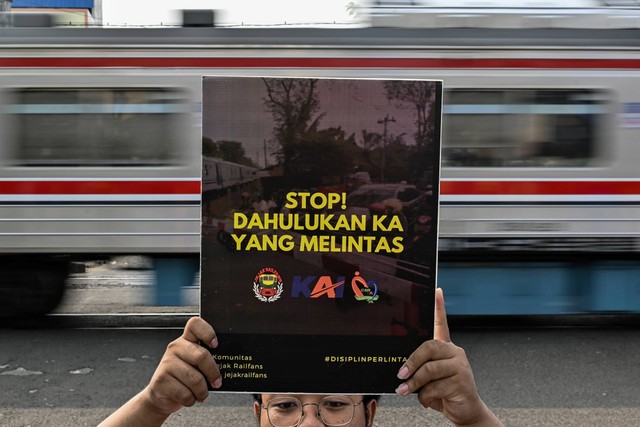 Warga dari komunitas fotografi pecinta kereta melakukan sosialisasi bahaya menerobos pintu perlintasan kereta kepada warga di kawasan Stasiun Kebayoran, Jakarta, Sabtu (9/12/2023). Foto: Sulthony Hasanuddin/ANTARA FOTO 