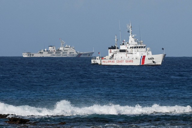 Sebuah kapal Penjaga Pantai China (kiri) dan kapal Penjaga Pantai Filipina (kanan) terlihat di dekat Pulau Thitu di Laut Cina Selatan yang disengketaka. Foto: JAM STA ROSA / AFP