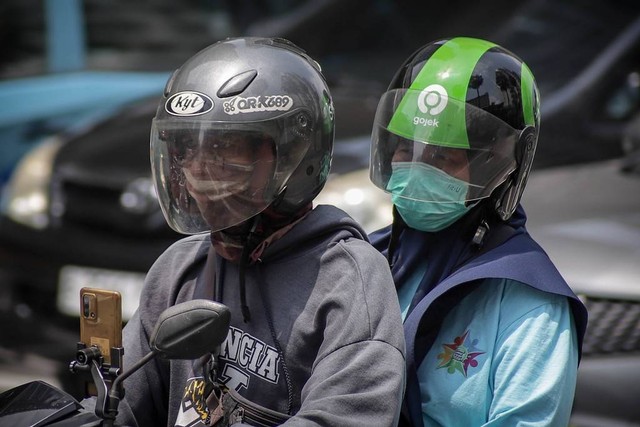 Pengendara sepeda motor dan penumpangnya juga terlihat mengenakan masker. Foto: Jamal Ramadhan/kumparan