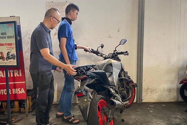 Sultan Rifat Alfatih bersama ayahnya, Fatih, mengecek motor yang dipakai Sultan saat kecelakaan di bengkel di kawasan Bintaro, Jaksel, Sabtu (16/12/2023). Foto: Thomas Bosco/kumparan