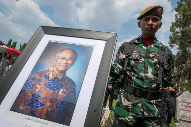 Seorang prajurit TNI berdiri di samping foto mendiang mantan Menteri Pertambangan dan Energi Kuntoro Mangkusubroto saat upacara pemakaman di Taman Makam Pahlawan (TMP) Kalibata, Jakarta, Minggu (17/12/2023). Foto: Aditya Pradana Putra/ANTARA FOTO