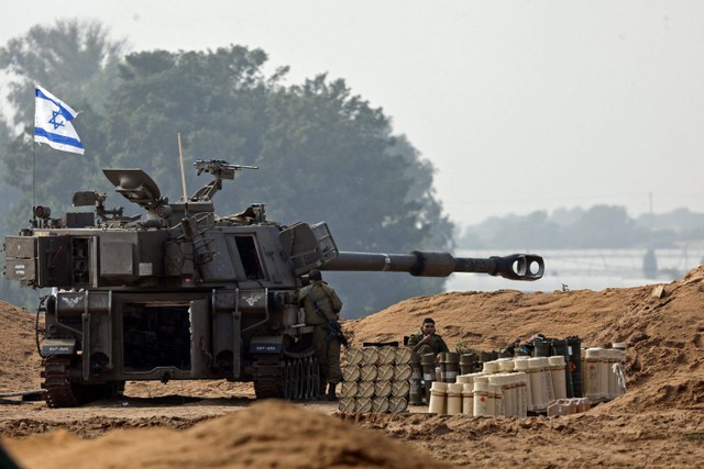 Seorang tentara Israel duduk di samping unit artileri di sisi Israel perbatasan Israel-Gaza, di tengah konflik yang sedang berlangsung antara Israel dan kelompok Islam Palestina Hamas, 14 Desember 2023. Foto: Amir Cohen/Reuters