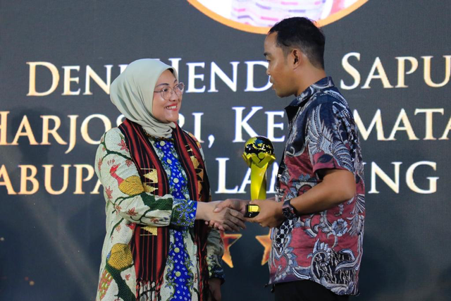 Menaker Ida Fauziyah berikan penghargaan Pekerja Migran Indonesia Purna Penempatan Berprestasi 1 kepada Deni Hendri Saputra dalam Peringatan Hari Migran Internasional 2023 di GOR Bumei Tuwah Bepadan Lampung Timur, Senin (18/12/2023). Foto: Kemnaker