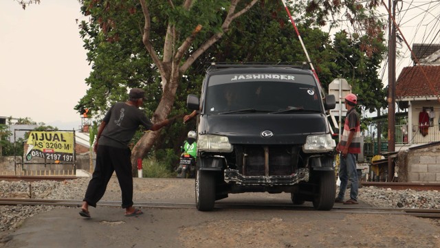 Penjaga perlintasan sebidang sedang menerima upah dari pengendara pada Minggu (26/11)siang. Sumber: Dokumentasi Pribadi