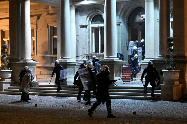 Unit polisi anti huru hara membubarkan pengunjuk rasa di dekat pintu masuk gedung dewan kota Beograd, Serbia, Minggu (24/12/2023). Foto: OLIVER BUNIC / AFP