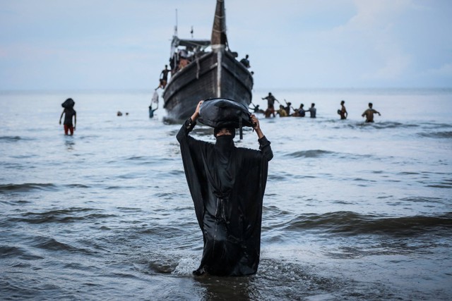 Seorang pengungsi Rohingya yang baru tiba berjalan ke pantai di Ulee Madon, provinsi Aceh, pada 16 November 2023. Foto: Amanda Jufrian / AFP