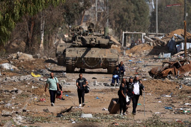 Warga Palestina yang melarikan diri ke utara berjalan melewati tank Israel selama gencatan senjatas Hamas dan Israel di jalan Salaheddine di distrik Zeitoun, Gaza pada 24 November 2023. Foto: MAHMUD HAMS / AFP