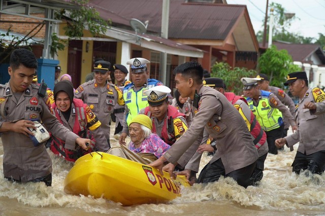 Polisi mengevakuasi korban banjir akibat luapan Sungai Batang Lubuh, Kecamatan Rambah, Kabupaten Rokan Hulu, Riau, Selasa (26/12/2023). Foto: Dok. Istimewa