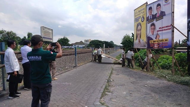 Alat peraga kampanye (APK) yang terpasang di sekitar pintu perlintasan kereta api ditertibkan Bawaslu Kabupaten Sleman, Rabu (27/12/2023). Foto: Bawaslu Sleman