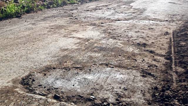 Kondisi jalan rusak berlubang yang diperbaiki seadanya dengan ditutupi tanah karena akan dilewati oleh Presiden Jokowi.