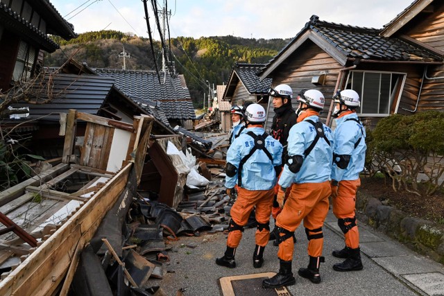 Petugas pemadam kebakaran memeriksa rumah-rumah kayu yang runtuh di Wajima, prefektur Ishikawa, Jepang pada Selasa (2/1/2024). Foto: Kazuhiro Nogi/AFP