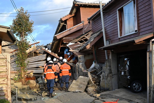 Petugas pemadam kebakaran memeriksa rumah-rumah kayu yang runtuh di Wajima, prefektur Ishikawa, Jepang pada Selasa (2/1/2024). Foto: Kazuhiro Nogi/AFP