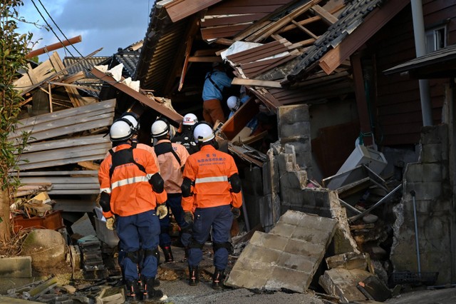 Petugas pemadam kebakaran memeriksa rumah-rumah kayu yang runtuh di Wajima, prefektur Ishikawa, Jepang pada Selasa (2/1/2024). Foto: Kazuhiro Nogi/AFP