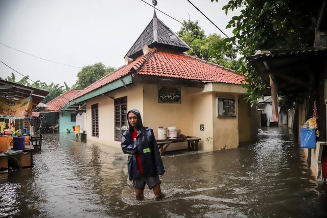 Warga berjalan di tengah banjir yang menggenangi permukiman di Jalan Rambai RT6/RW2, Kramat Pela, Kebayoran Baru, Jakarta Selatan, Sabtu (6/1/2024). Foto: Jamal Ramadhan/kumparan