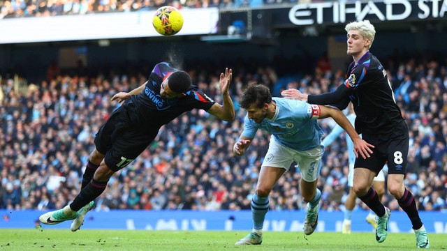 Brodie Spencer dari Huddersfield Town berusaha mengambil bola bersama Ruben Dias dari Manchester City dalam pertandingan Manchester City vs Huddersfield Town di Stadion Etihad, Manchester, Inggris - 7 Januari 2024. Foto: Reuters/Carl Recine