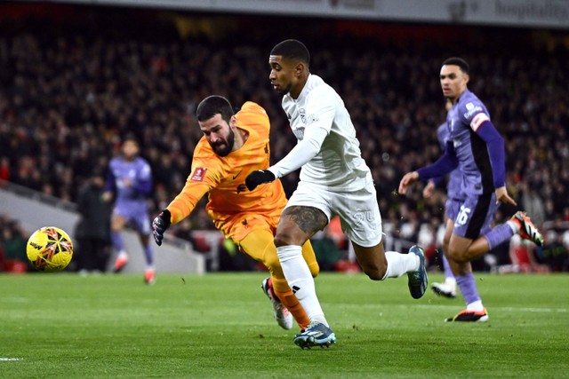 Pemain Arsenal Reiss Nelson berusaha melewati penjaga gawang Liverpool Alisson pada pertandingan Piala FA di Stadion Emirates, London, Inggris, Minggu (7/1/2024). Foto: Dylan Martinez/REUTERS