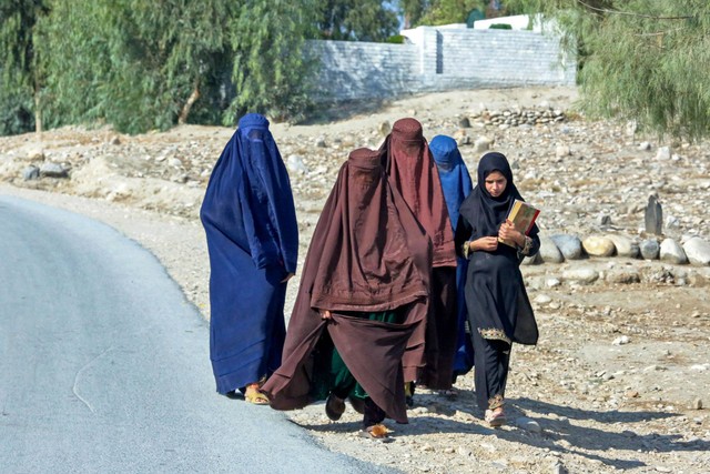 Wanita Afghanistan berburqa berjalan di sepanjang jalan di pinggiran Jalalabad pada 22 Oktober 2023. Foto: SHAFIULLAH KAKAR/AFP