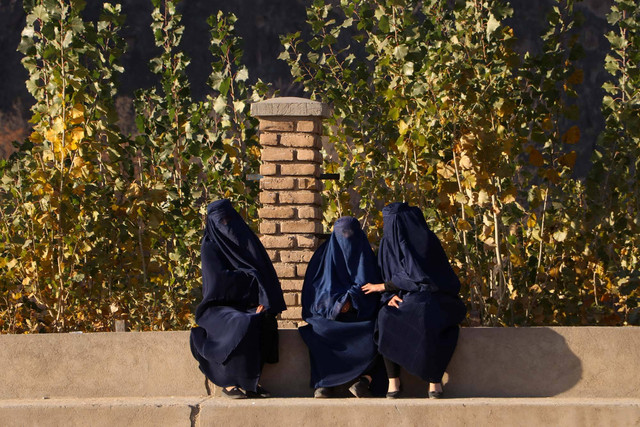 Wanita berpakaian burqa Afghanistan duduk di sepanjang jalan di distrik Fayzabad di provinsi Badakhshan pada 6 Desember 2023. Foto: OMER ABRAR/AFP