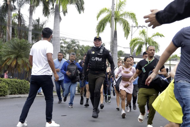 Polisi mengevakuasi staf stasiun televisi publik TC setelah sekelompok pria bersenjata menerobos masuk ke lokasi syuting saat siaran langsung, di Guayaquil, Ekuador, Selasa, 9 Januari 2024. Foto: AP/Cesar Munoz