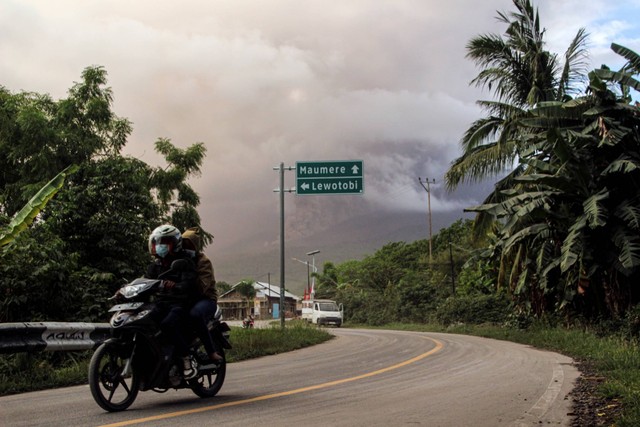 Pengendara motor melintas dengan berlatar belakang Gunung Lewotobi Laki-laki yang erupsi di Desa Nobo, Ile Bura, Flores Timur, NTT, Rabu (10/1/2024). Foto: Mega Tokan/ANTARA FOTO