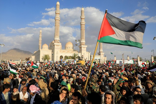 Para pengunjuk rasa, salah satunya memegang bendera Palestina, mengambil bagian dalam aksi solidaritas dengan rakyat Gaza di ibu kota Sanaa yang dikuasai Huthi pada (5/1/2024) di tengah pertempuran yang sedang berlangsung antara Israel. Foto: Mohammed Huwais / AFP