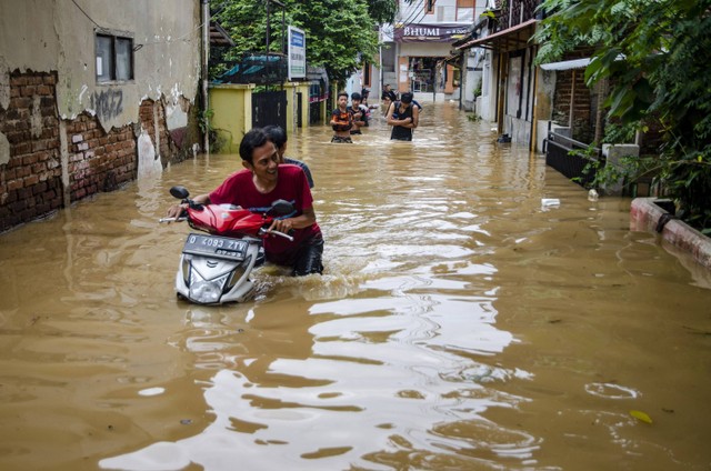 Warga mendorong sepeda motor melewati banjir di Dayeuhkolot, Kabupaten Bandung, Jawa Barat, Jumat (12/1/2024). Foto: ANTARA FOTO/Novrian Arbi