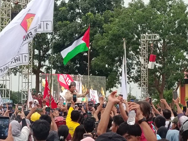 Prabowo Subianto meminta bendera Palestina yang dibawa masyarakat dan mengibarkannya di atas panggung. Foto: Zamachsyari/kumparan