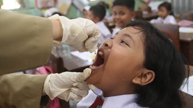 Petugas kesehatan memberikan imunisasi polio kepada siswa di SD Negeri Tempurejo 1, Kediri, Jawa Timur, Senin (15/1/2024). Foto: ANTARA FOTO/Prasetia Fauzani