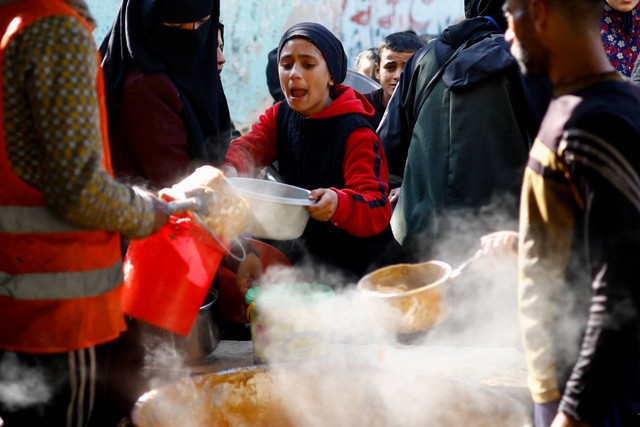 Warga Palestina menunggu untuk menerima makanan yang dimasak oleh dapur amal, di tengah kekurangan pasokan makanan, di Rafah, selatan Jalur Gaza, 16/1/2024). Foto: Ibraheem Abu Mustafa/REUTERS