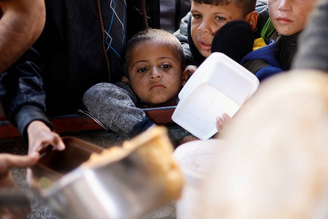 Anak-anak Palestina mengantre untuk menerima makanan yang dimasak oleh dapur amal, di tengah kekurangan pasokan makanan, di Rafah, selatan Jalur Gaza, 16/1/2024). Foto: Ibraheem Abu Mustafa/REUTERS