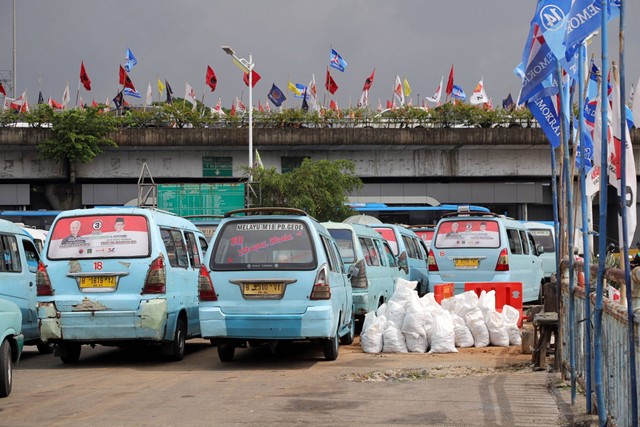 Alat peraga kampanye (APK) tertempel pada kaca angkot di Terminal Kampung Melayu Jakarta, Rabu (17/1/2024). Foto: Jamal Ramadhan/kumparan