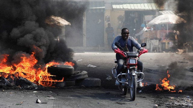 Seorang pengendara sepeda motor melewati barikade yang terbakar, salah satu dari banyak di Port-au-Prince, Haiti 18 Januari 2024. Foto: REUTERS/Ralph Tedy Erol