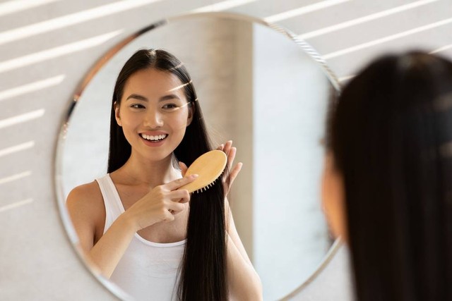Ilustrasi perempuan menyisir rambut sehat dan tebal. Foto: Prostock-studio/Shutterstock