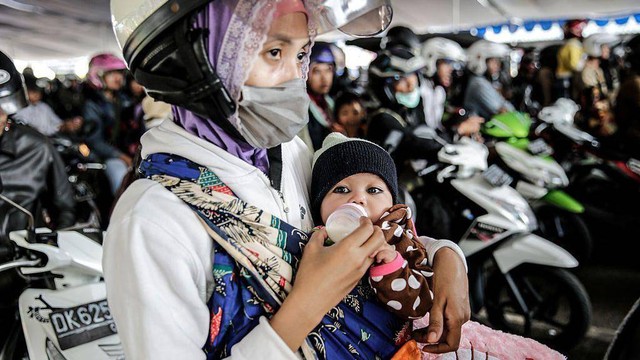 Seorang ibu memberikan sebotol susu kepada bayinya di Pelabuhan Gilimanuk, Bali.  WHO merekomendasikan para ibu agar menyusui bayi mereka selama enam bulan pertama secara eksklusif jika memungkinkan.