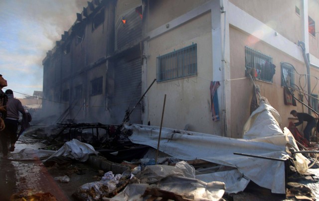 Warga Palestina mencoba memadamkan api di gedung pusat pelatihan kejuruan UNRWA yang digunakan para pengungsi sebagai tempat berlindung usai diserang tank Israel di Khan Younis, Jalur Gaza selatan, Rabu (24/1/2024). Foto: Ramez Habboub/AP PHOTO