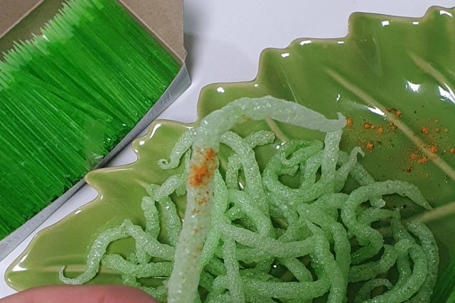 Seseorang memegang "tusuk gigi goreng hijau" yang menjadi viral mengikuti tren media sosial di Busan, Korea Selatan. Foto: X/@hee_2458 dan b_chuchu_ via REUTERS