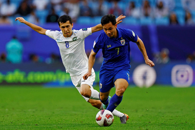 Pemain Thailand Supachok Sarachat beraksi bersama pemain Uzbekistan Jamshid Iskanderov di Stadion Al Janoub, Al Wakrah, Qatar, Selasa (30/1/2024). Foto: Rula Rouhana/REUTERS