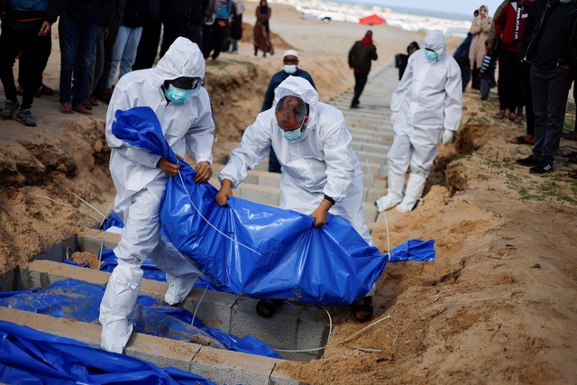 Orang-orang menguburkan warga Palestina yang tewas akibat serangan Israel, setelah jenazah mereka dibebaskan oleh Israel, di kuburan massal di Rafah, di Jalur Gaza selatan, Selasa (30/1/2024). Foto: Mohammed Salem/REUTERS