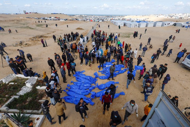 Orang-orang menguburkan warga Palestina yang tewas akibat serangan Israel, setelah jenazah mereka dibebaskan oleh Israel, di kuburan massal di Rafah, di Jalur Gaza selatan, Selasa (30/1/2024). Foto: Mohammed Salem/REUTERS