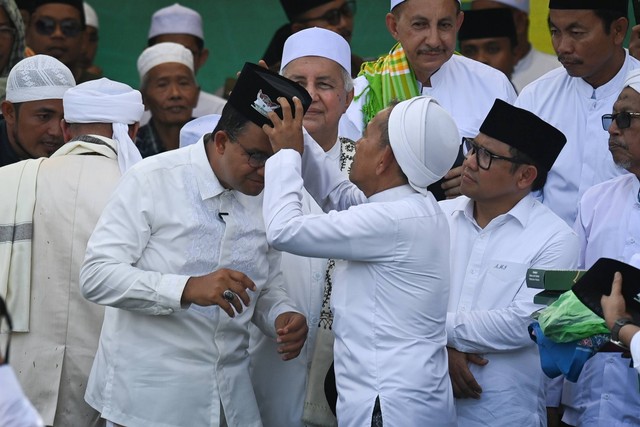 Salah satu ulama mengenakan peci tanda dukungan untuk capres-cawapres nomor urut 1 Anies Baswedan (kiri) dan Muhaimin Iskandar (kanan) saat berkampanye di Lapangan Pondok Pesantren Gunung Sari, Pamekasan, Jawa Timur, Rabu (31/1/2024). Foto: Aditya Pradana Putra/ANTARA FOTO