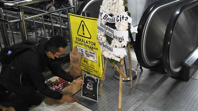 Seorang penumpang kereta melakukan aksi di depan bunga duka cita atas rusaknya satu eskalator di Stasiun Bekasi, Jawa Barat, Rabu (31/1/2024). Foto: ANTARA FOTO/ Fakhri Hermansyah