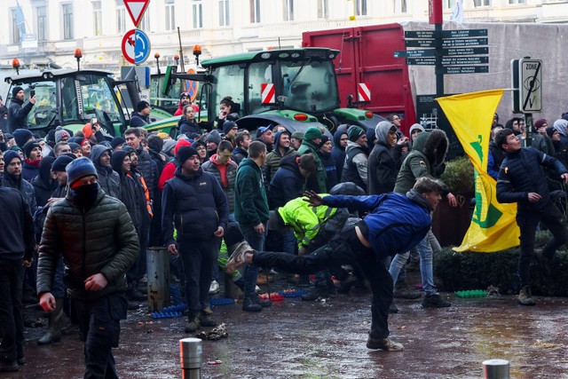 Aksi demonstran saat bentrok dengan polisi yang menyemprotkan air di depan markas besar Uni Eropa ketika para petani Belgia menggunakan traktor mereka untuk memblokir jalan saat KTT UE di Brussels, Belgia, Kamis (1/2/2024). Foto: Yves Herman/Reuters
