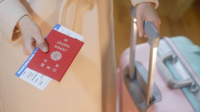 Ilustrasi turis memegang paspor Jepang. Foto: Ammily CP/Shutterstock