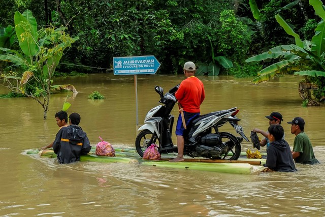 Warga menggotong motor melintasi banjir di Kampung Surianeun, Pandeglang, Banten, Minggu (4/2/2024). Foto: Muhammad Bagus Khoirunas/Antara Foto