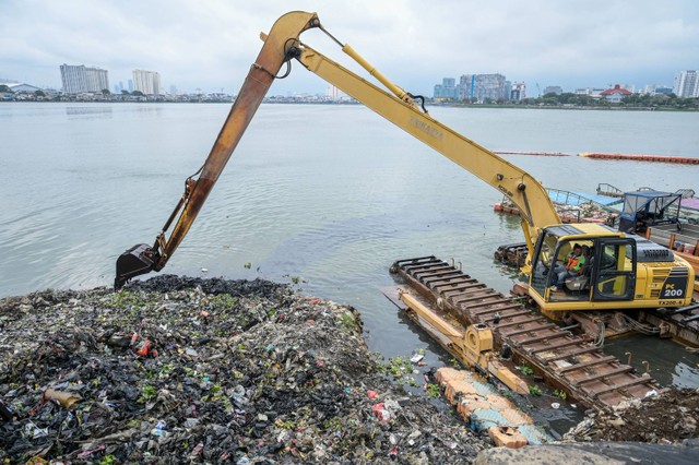 Petugas Unit Penanganan Sampah Badan Air DInas Lingkungan Hidup DKI Jakarta mengoperasikan alat berat membersihkan Waduk Pluit dari sampah, di Jakarta, Senin (5/2/2024). Foto: Bayu Pratama S/Antara Foto