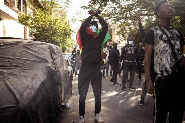 Demonstran memberi isyarat kepada polisi di luar Majelis Umum di Plateau, Dakar, Senegal, Senin (5/2/2024). Foto: John Wessels/AFP