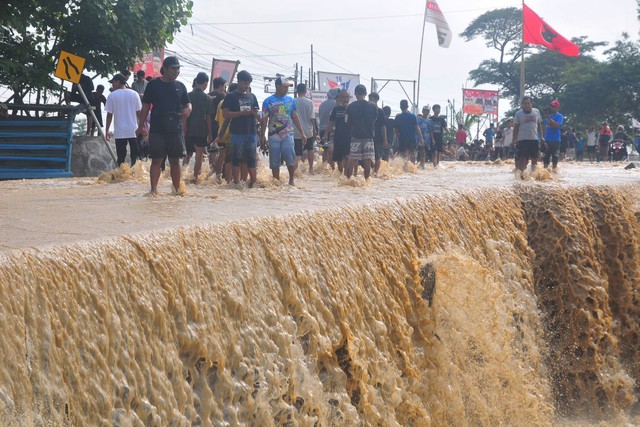 Warga menyaksikan jalan Gubug-Semarang yang ambrol akibat diterjang banjir di Desa Gubug, Gubug, Grobogan, Jawa Tengah, Selasa (6/2/2024). Foto: Yusuf Nugroho/ANTARA FOTO