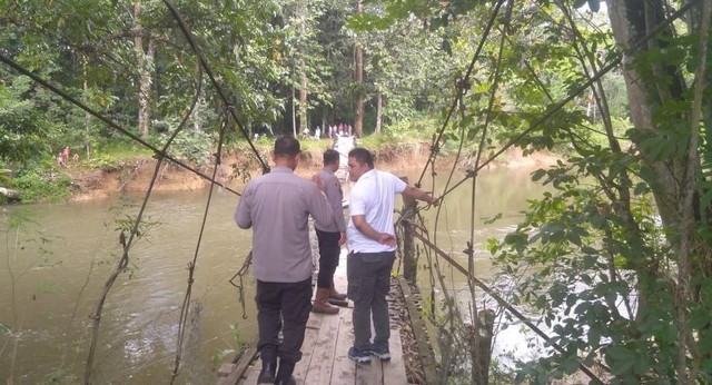 Polisi bersama Kepala Desa mengecek kondisi jembatan gantung Aur Tokam, Dusun Sulang Betung, Desa Sungai Sambang, yang ambruk diterjang banjir. Foto: Dok. Polres Sekadau