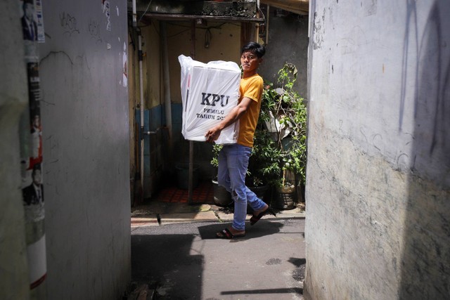 Petugas membawa kotak serta surat suara Pemilu 2024 ke dalam gang pemukiman padat penduduk di kawasan Petamburan, Kecamatan Tanah Abang Jakarta Pusat, Selasa (13/2/2024). Foto: Jamal Ramadhan/kumparan