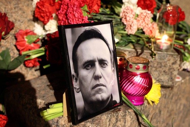 Bunga dan potret pemimpin oposisi Rusia Alexei Navalny ditempatkan di monumen korban penindasan politik setelah kematiannya, di Saint Petersburg, Rusia, Jumat (16/2/2024). Foto: Stringer/REUTERS